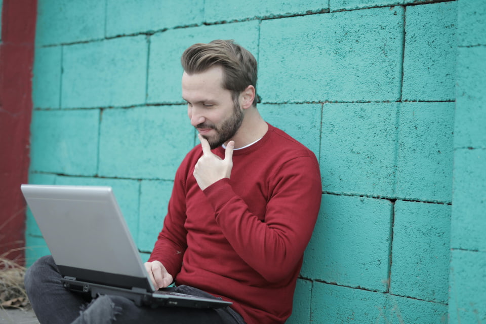 man with hand on chin looking at computer